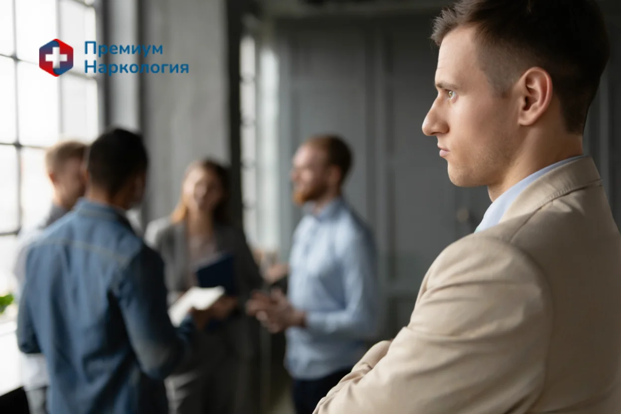 Мужчина стоит в стороне от своих коллег